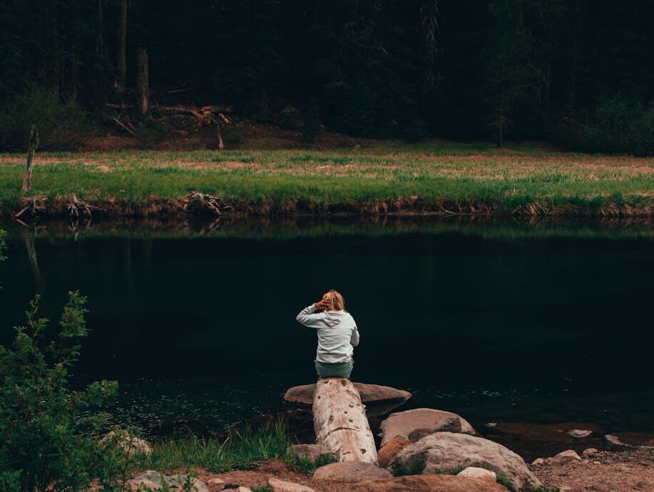 a woman sitting on rocks by the riverside