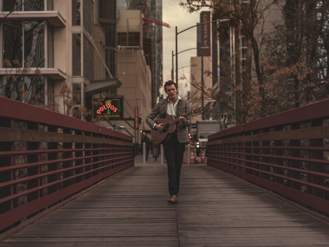 man playing guitar in a footbridge